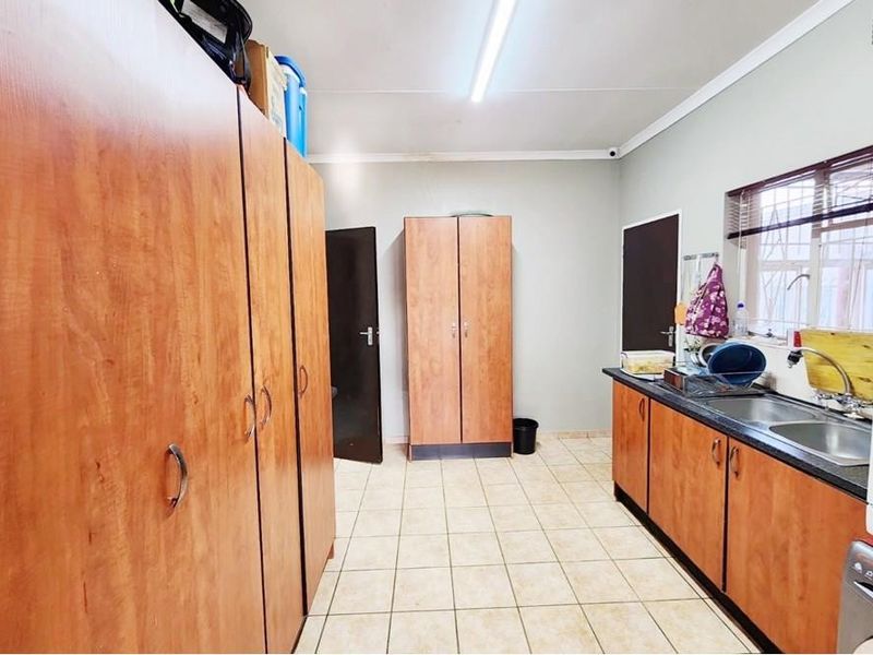Functional laundry room featuring extensive built-in cabinetry, tiled flooring, and a double basin sink with window access.