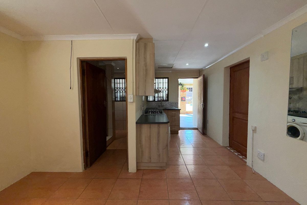 A functional kitchen area featuring built-in cabinetry, a gas hob, and tiled flooring, with direct access to an outdoor space.