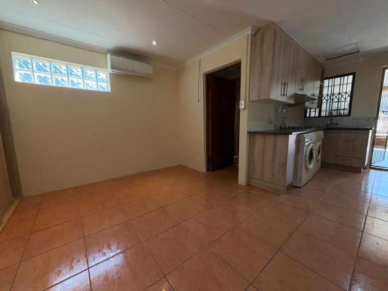 Open plan kitchen and living area featuring tiled flooring, built-in cabinetry, and a split-system air conditioner.