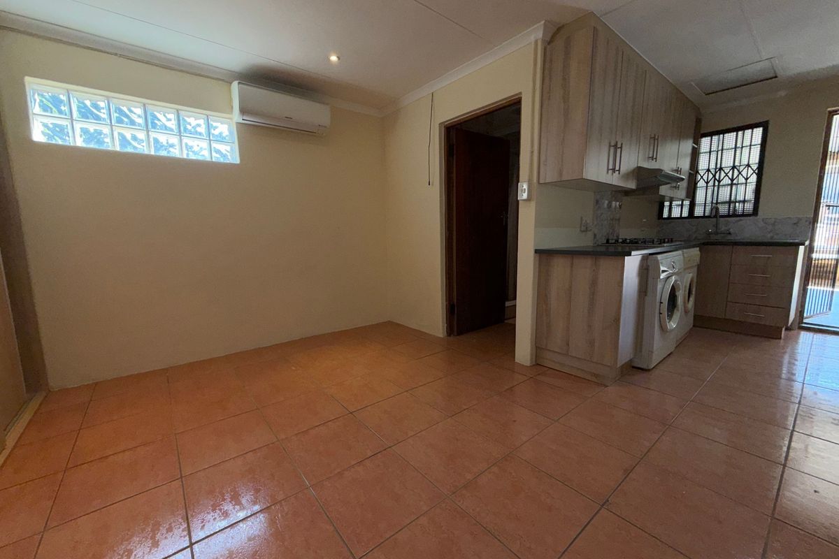 Open plan kitchen and living area featuring tiled flooring, built-in cabinetry, and a split-system air conditioner.