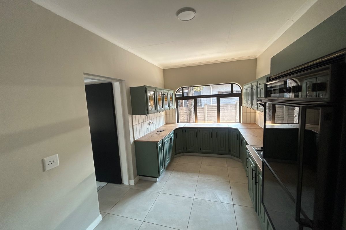 A clean, functional kitchen featuring green cabinetry, wood-look countertops, tiled backsplash, and a built-in oven, offering a bright and practical workspace.