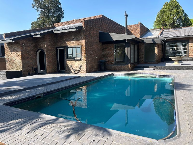 A well-maintained outdoor pool area featuring a paved patio, brick exterior walls, and a swimming pool, ideal for outdoor relaxation and entertainment.