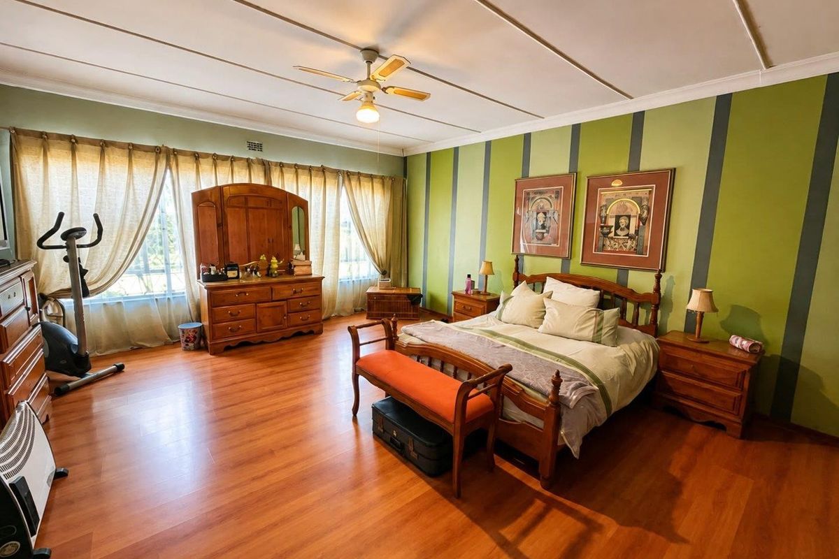 Spacious bedroom featuring laminate flooring, a ceiling fan, and large windows with natural light.