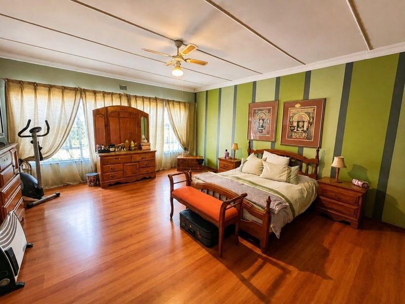 Spacious bedroom featuring laminate flooring, a ceiling fan, and large windows with natural light.