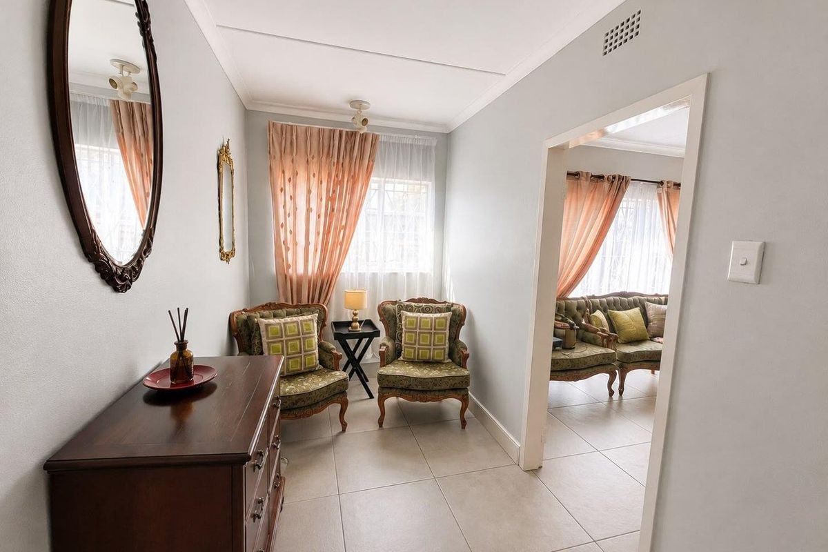 A bright living area featuring neutral tiled flooring and coved ceilings, providing a clean and well-maintained space with good natural light.