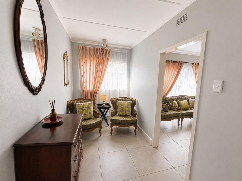 A bright living area featuring neutral tiled flooring and coved ceilings, providing a clean and well-maintained space with good natural light.