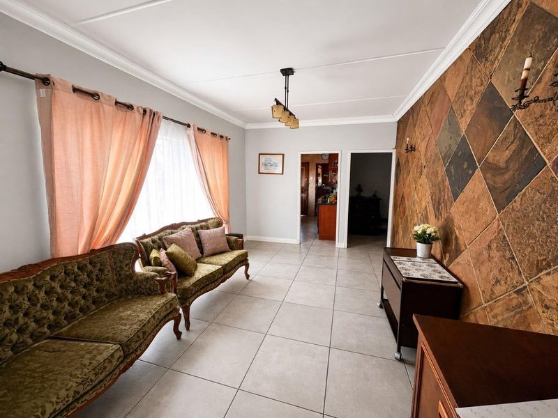 A living room featuring large format floor tiles, a distinctive diamond-patterned slate feature wall, and crown molding, providing a neutral base for updates.