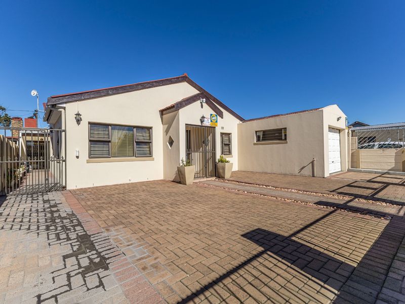 Front exterior view of a well-maintained house featuring a paved driveway, single garage, and secure gated entrance.