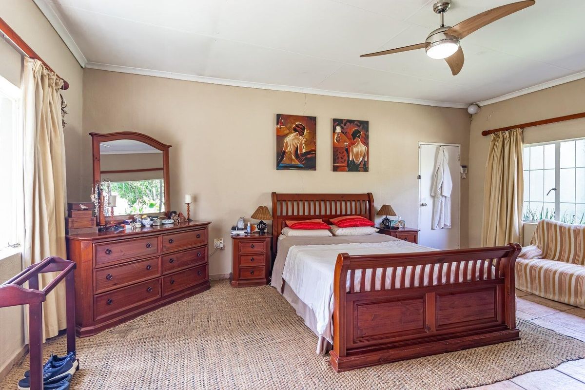 A spacious bedroom featuring a ceiling fan, tiled flooring, and neutral wall finishes, offering a functional layout with natural light.