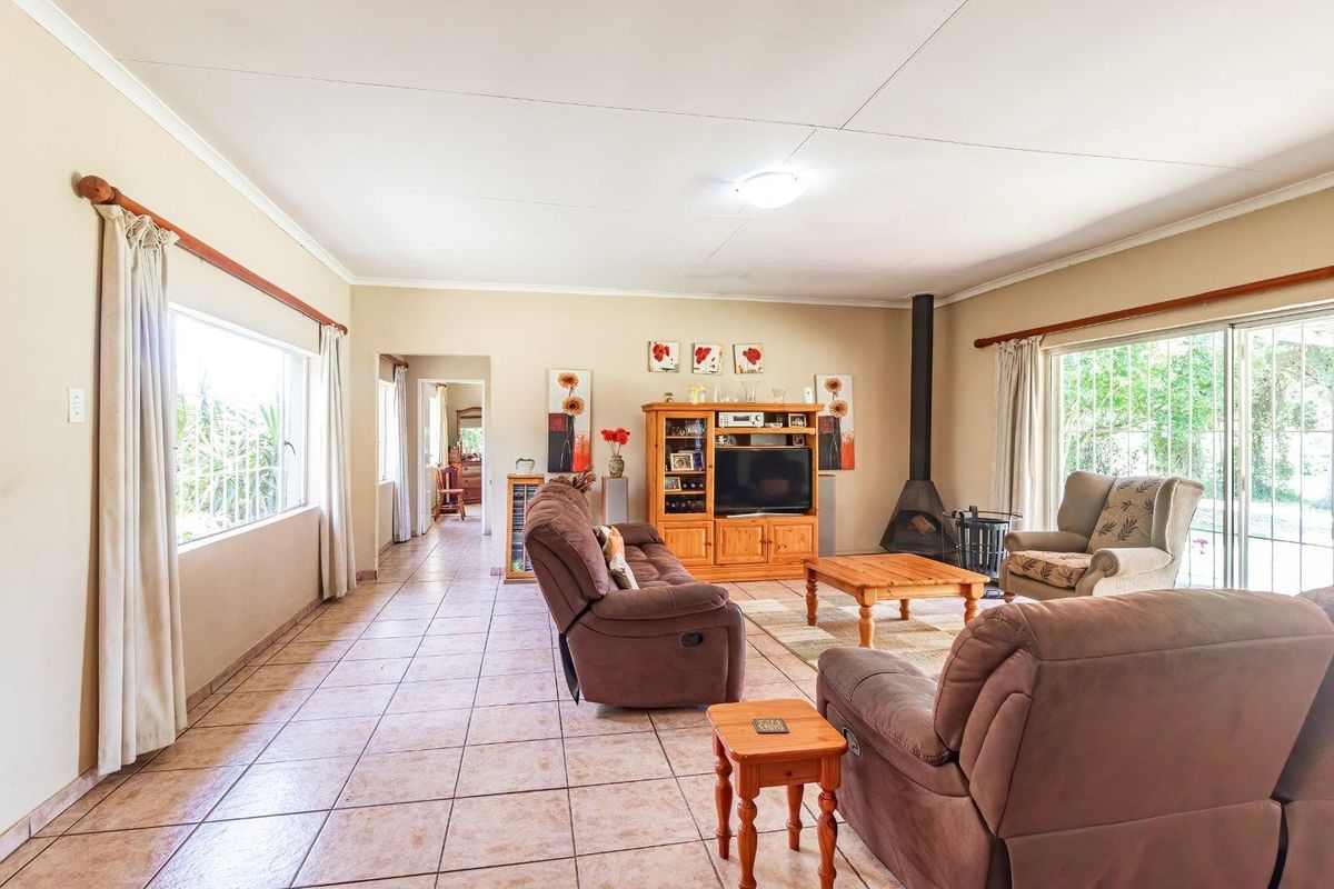 Spacious living room featuring tiled flooring, a freestanding fireplace, and large windows with security bars, offering a bright and functional layout.