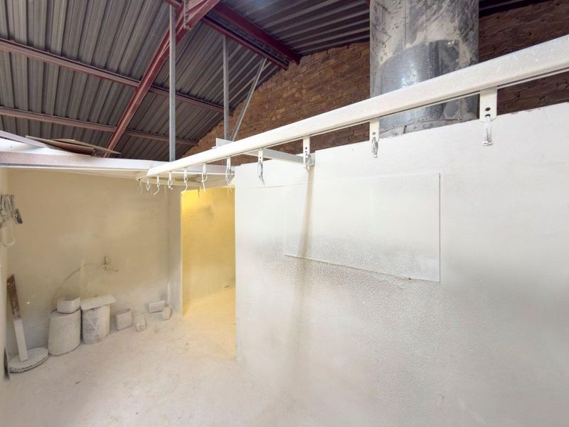 Industrial utility space featuring exposed steel roof trusses, brickwork walls, and an overhead rail system, suitable for workshop or storage use.
