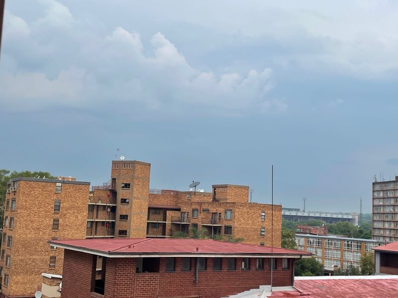 An elevated view of the surrounding apartment complex buildings featuring brick facades and corrugated metal roofing under a cloudy sky.