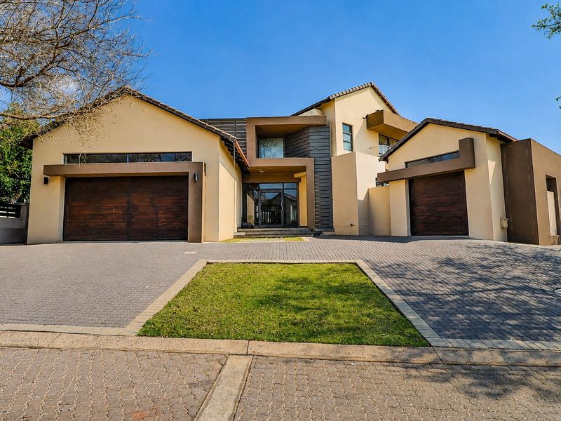 Modern double-story residence featuring a paved driveway, double garage, and contemporary architectural facade with clean lines and neutral tones.