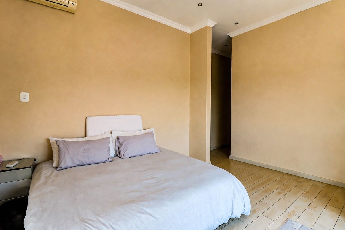 A bedroom featuring tiled flooring, recessed downlighting, and a wall-mounted air conditioning unit.