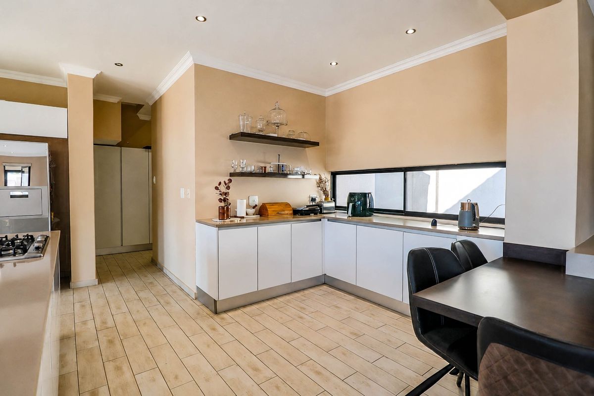 Modern kitchen featuring white cabinetry, a gas hob, tiled flooring, and floating shelves, creating a clean and functional culinary space.