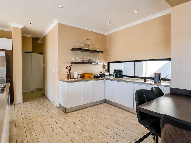 Modern kitchen featuring white cabinetry, a gas hob, tiled flooring, and floating shelves, creating a clean and functional culinary space.