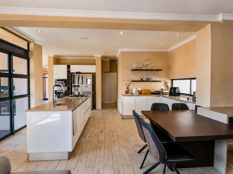Spacious open-plan kitchen featuring a central island, modern cabinetry, built-in appliances, and tiled flooring, seamlessly integrated with the dining area.