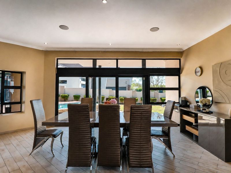 A bright dining room featuring tiled flooring, recessed lighting, and large sliding glass doors that provide direct access to the outdoor pool area.