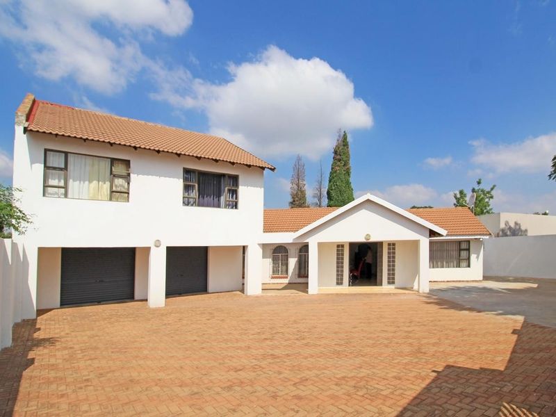 A well-maintained double-story house featuring a spacious paved driveway, double garage, and a covered entrance with a classic tiled roof.
