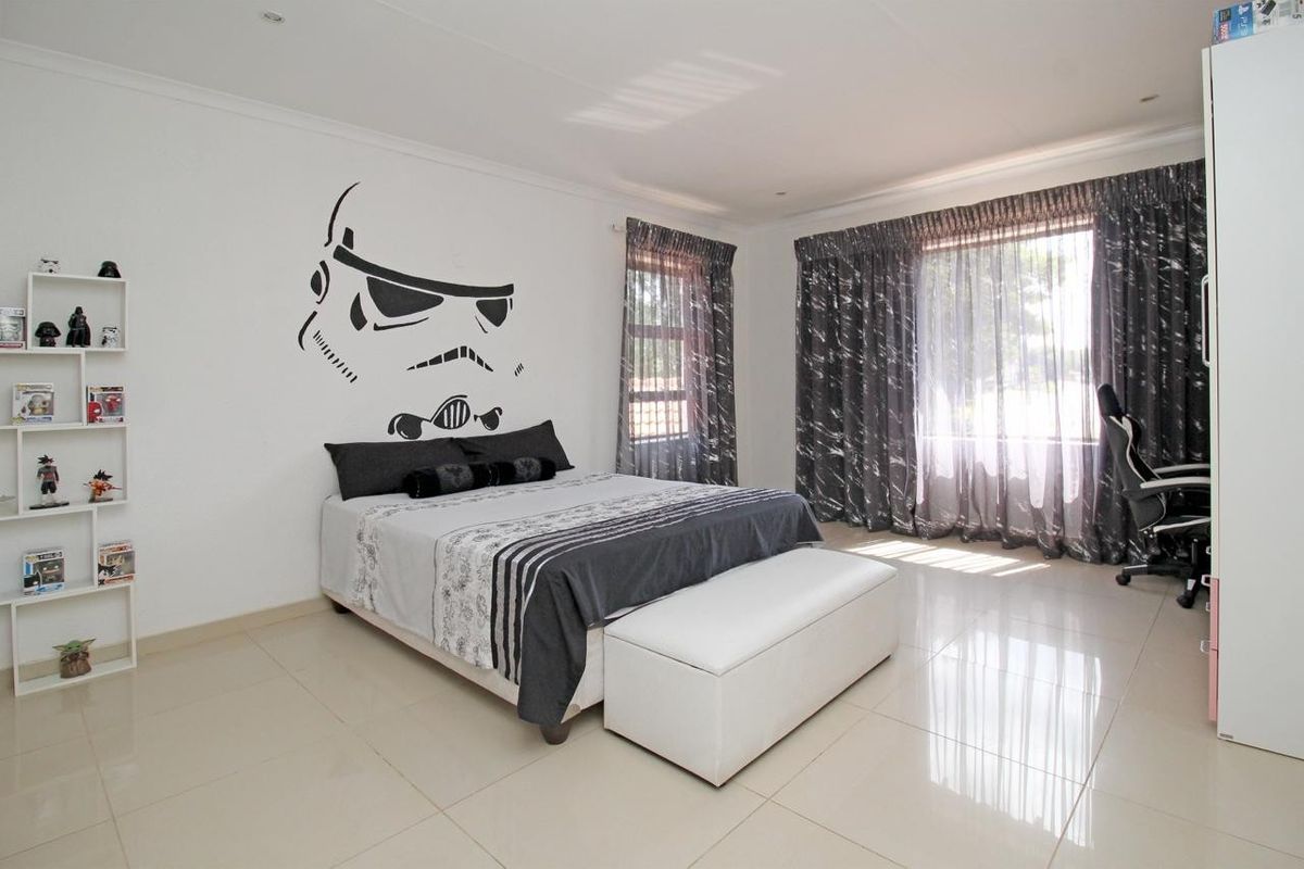 A spacious bedroom featuring neutral tiled flooring, recessed lighting, and large windows with curtain tracks, offering a clean and well-maintained living space.