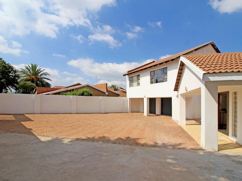 Spacious paved driveway leading to a double garage and covered entrance of a well-maintained two-story residential property.