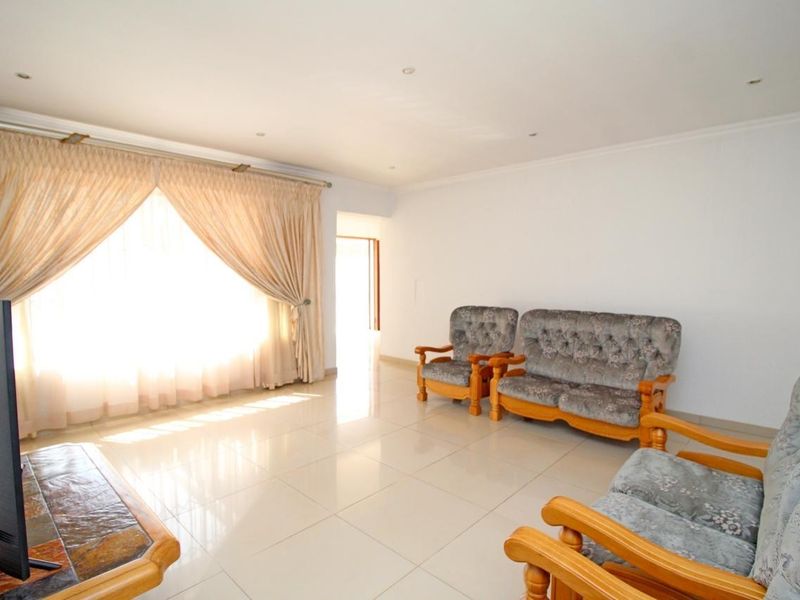 A bright living room featuring neutral tiled flooring and recessed downlighting, offering a clean and functional space for relaxation.