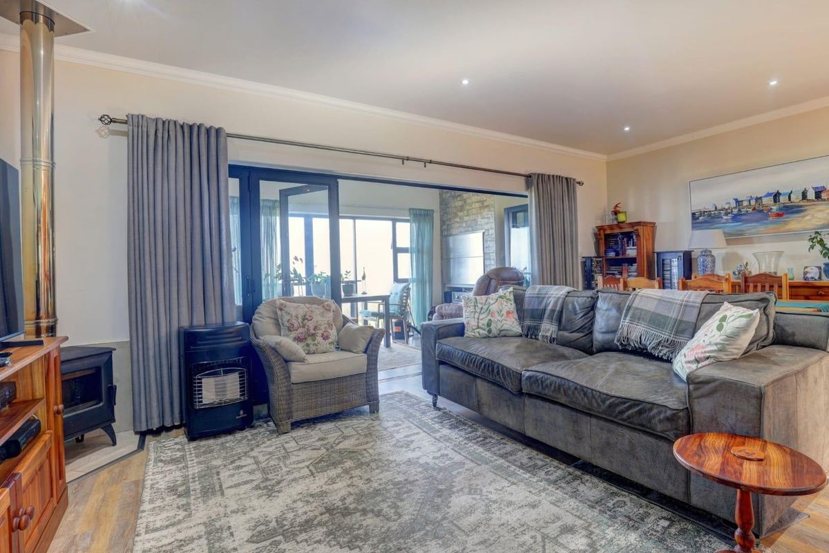 A comfortable living room featuring a wood-burning stove, recessed lighting, and large sliding glass doors that open onto an adjacent patio area.