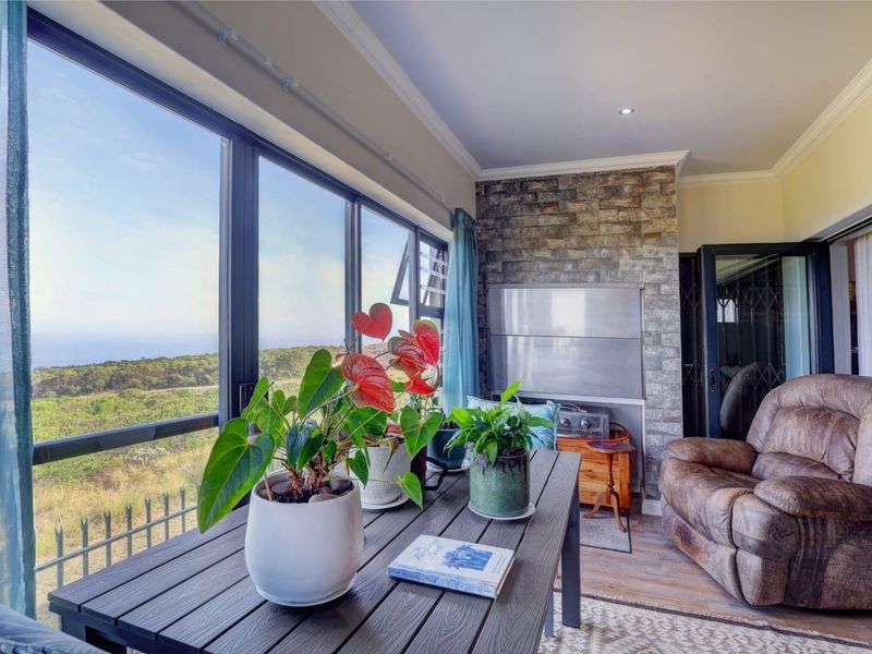 Enclosed patio area featuring a stone accent wall, built-in braai, and expansive windows offering scenic landscape views.