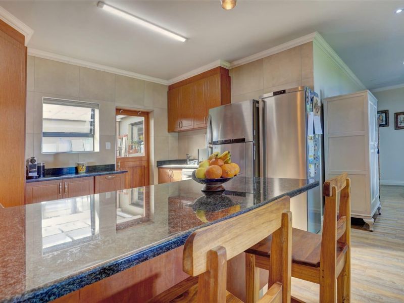 A functional kitchen featuring granite countertops, wooden cabinetry, and a tiled backsplash, offering a practical layout with integrated storage and workspace.