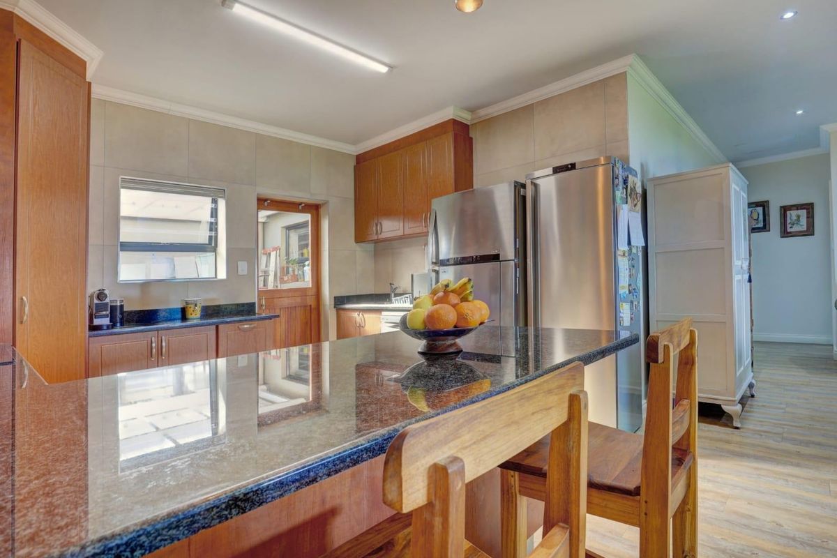 A functional kitchen featuring granite countertops, wooden cabinetry, and a tiled backsplash, offering a practical layout with integrated storage and workspace.
