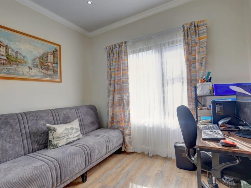 A functional bedroom or home office space featuring laminate flooring, recessed downlighting, and decorative coving.