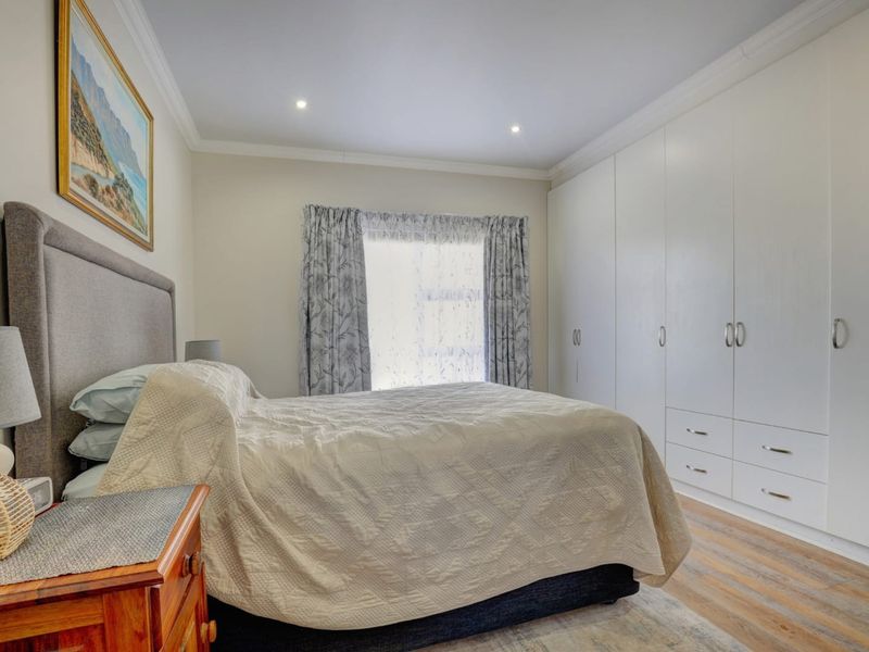 A well-maintained bedroom featuring extensive floor-to-ceiling built-in cupboards, recessed downlighting, and modern laminate flooring.