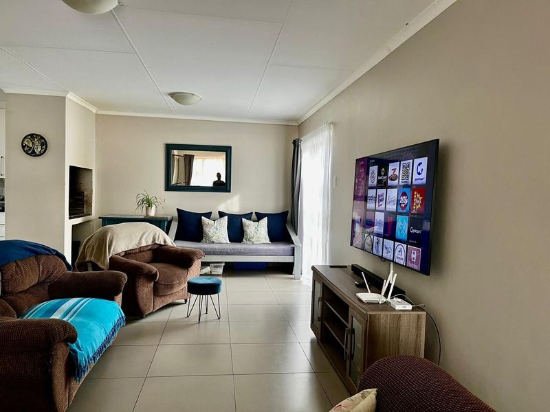 A comfortable living room featuring tiled flooring, a built-in fireplace, and a sliding glass door providing natural light.