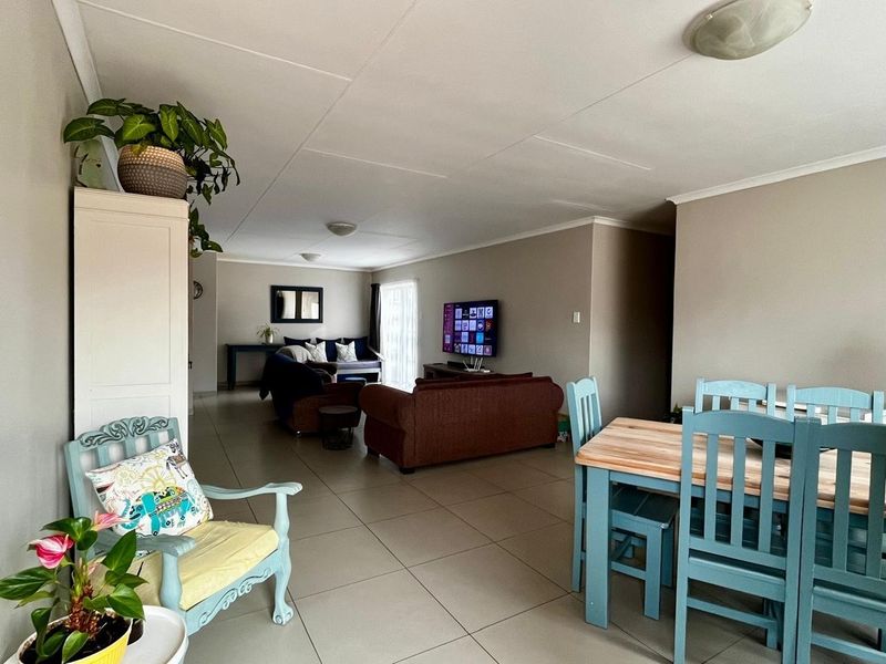 An open-plan living and dining area featuring neutral wall tones, tiled flooring, and a sliding glass door providing access to the exterior.