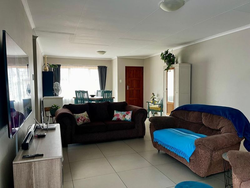 Spacious open-plan living and dining area featuring neutral wall tones and large format floor tiles, providing a versatile layout for family living.