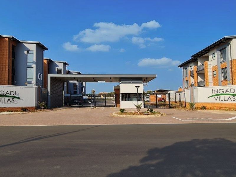 The main entrance and security gatehouse of Ingadi Villas, featuring modern multi-story residential buildings, perimeter walls, and controlled access infrastructure.