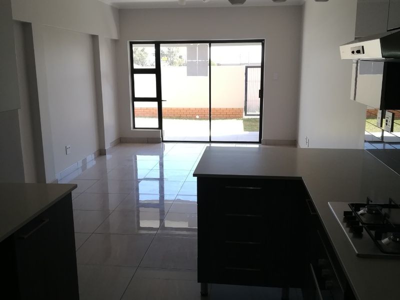 Open-plan living and kitchen area featuring modern cabinetry, gas hob, tiled flooring, and sliding door access to the rear patio.