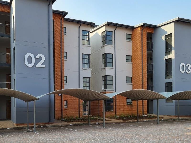 Exterior view of a modern multi-story townhouse complex featuring brick and rendered facades with dedicated covered parking bays.