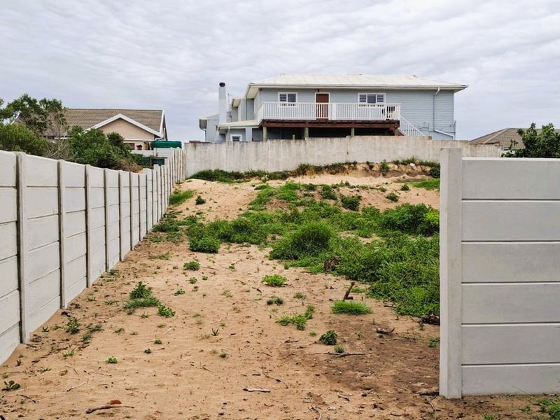 A vacant residential plot featuring a precast concrete boundary wall and sandy terrain, offering a blank canvas for future development.