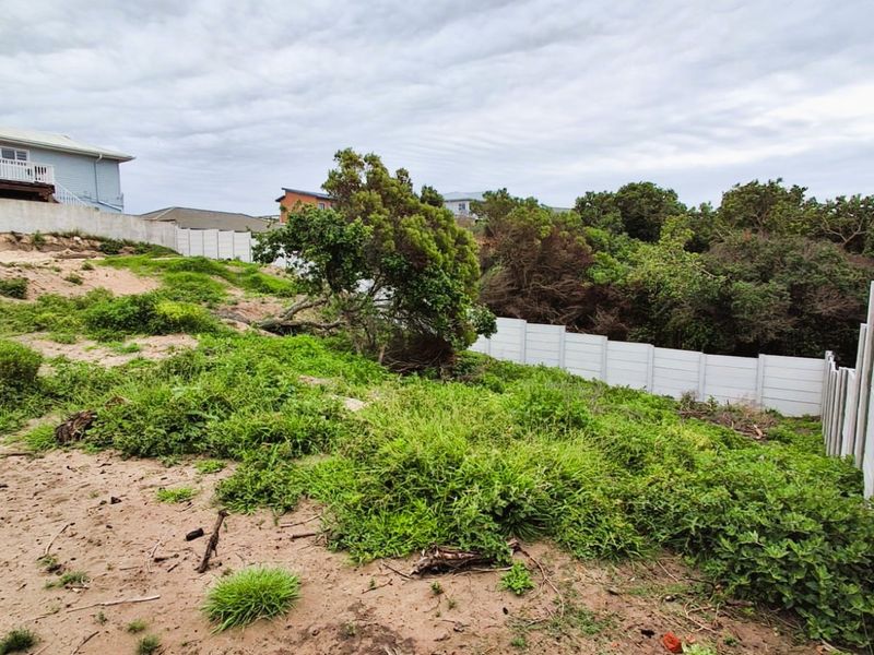 A sloped, unimproved residential vacant plot featuring natural vegetation and a precast concrete boundary wall.