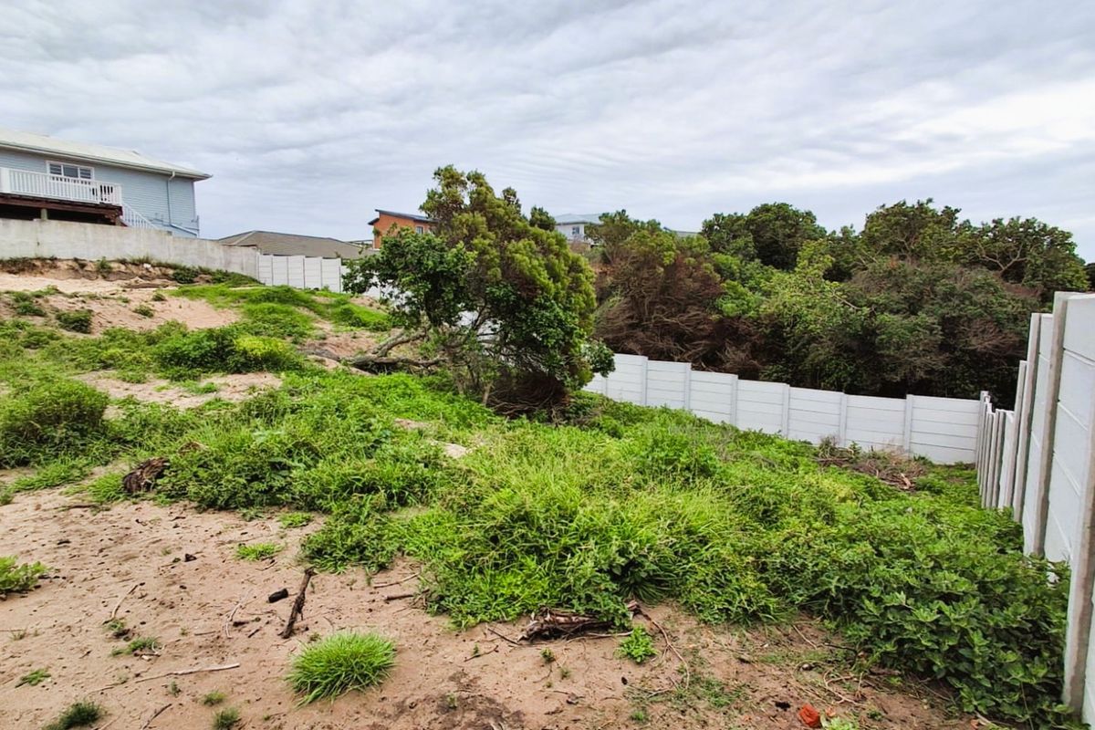 A sloped, unimproved residential vacant plot featuring natural vegetation and a precast concrete boundary wall.