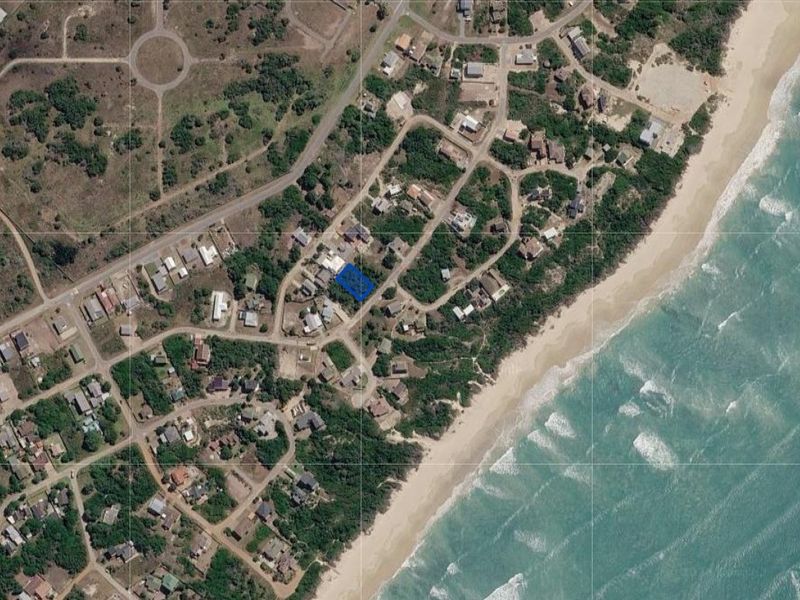 Aerial view of a vacant residential land parcel located within a coastal estate, highlighting its proximity to the beach and surrounding neighborhood infrastructure.