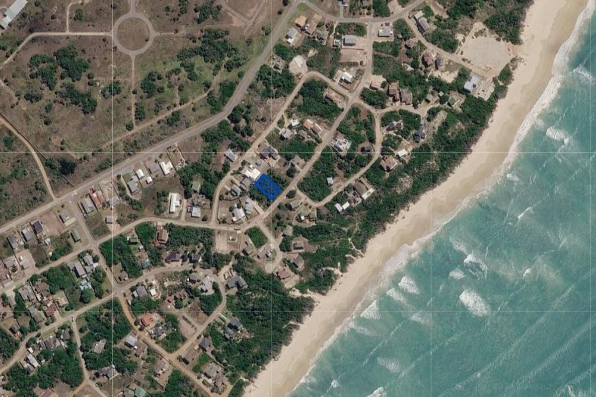 Aerial view of a vacant residential land parcel located within a coastal estate, highlighting its proximity to the beach and surrounding neighborhood infrastructure.