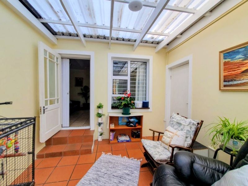 A covered patio area featuring terracotta floor tiles and a translucent roof, providing a functional transition space between the interior and exterior.