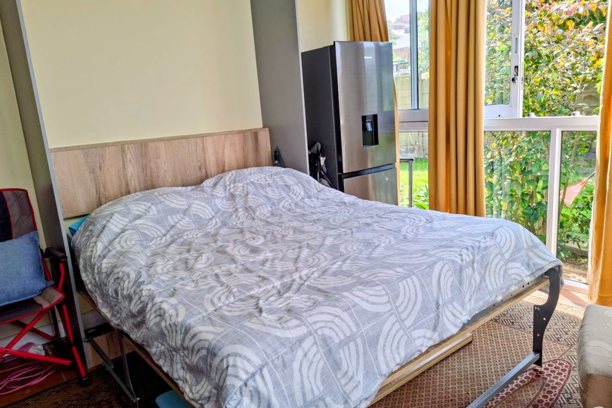 A bedroom featuring a large window and sliding door access, providing natural light and views of the garden area.