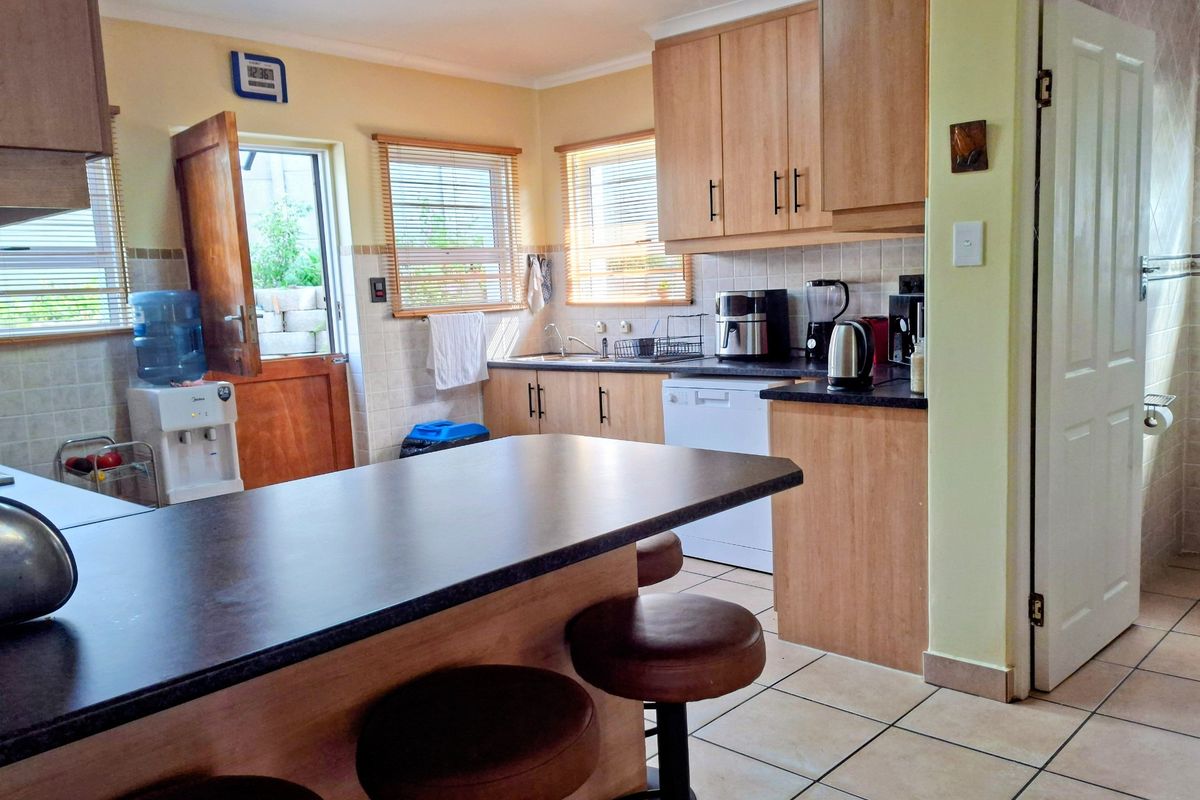 Functional kitchen featuring laminate cabinetry, dark countertops, a breakfast nook, and tiled flooring with direct access to the exterior.