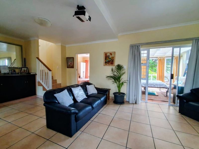 Spacious living room featuring tiled flooring, a staircase, and sliding glass doors providing direct access to the outdoor patio area.