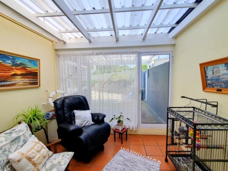 Enclosed patio area featuring terracotta floor tiles and a translucent roof, providing a bright transition space to the rear exterior.