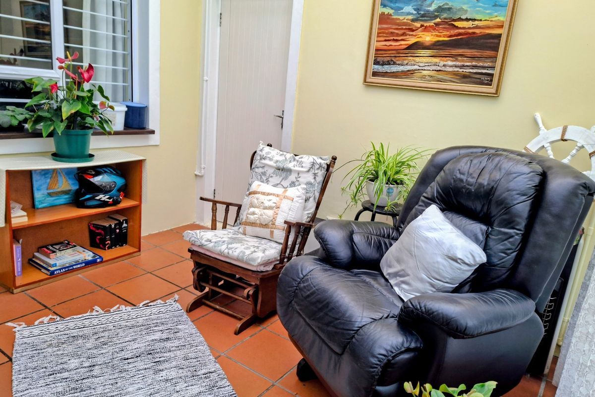 A cozy living area featuring terracotta floor tiles, a window with security bars, and a neutral wall finish.