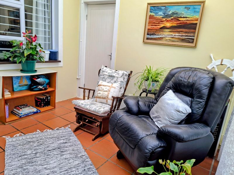 A cozy living area featuring terracotta floor tiles, a window with security bars, and a neutral wall finish.